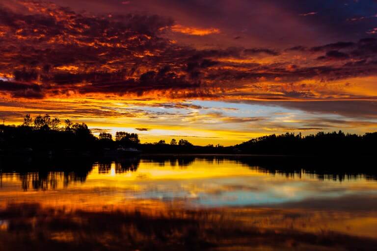 Breathtaking sunset over calm lake with vivid reflections in a colorful sky.