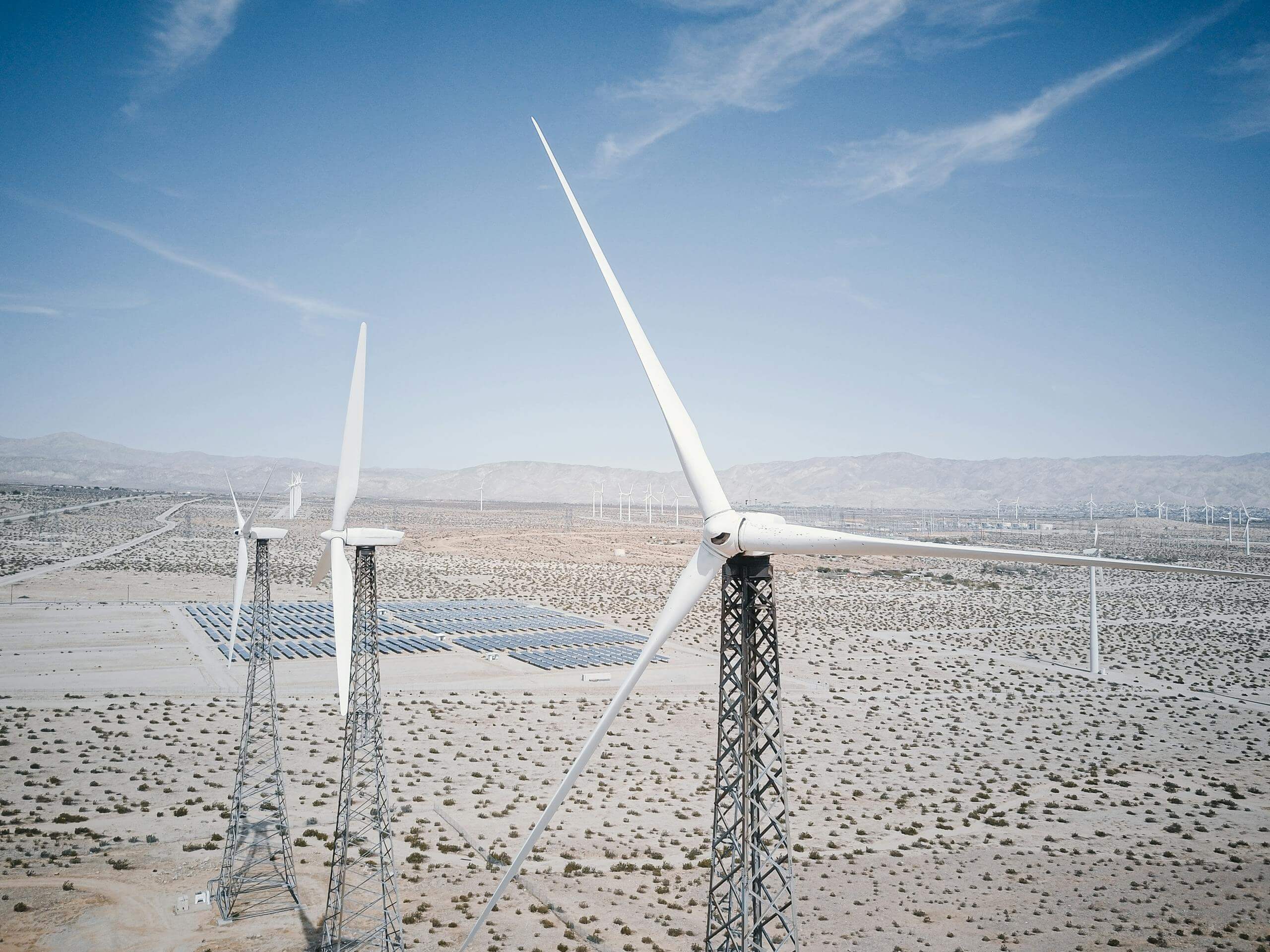 Wind turbines and solar panels generating renewable energy in a desert landscape.